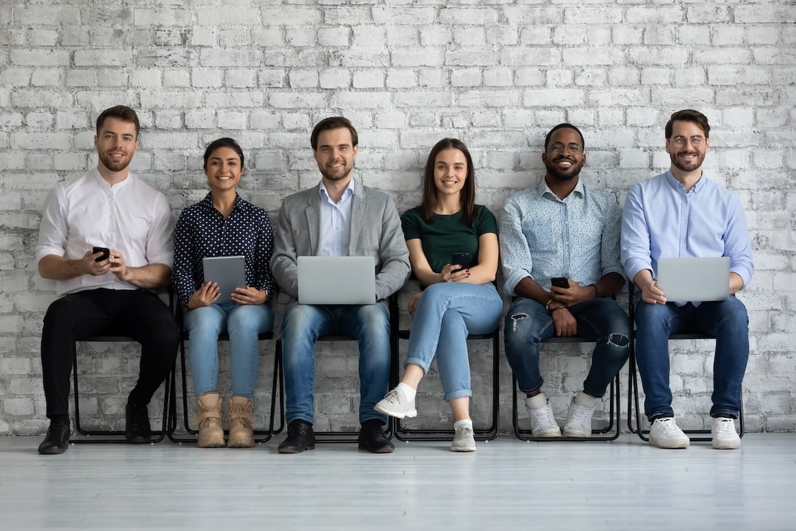 A group of diverse young workers sitting nearby and working together