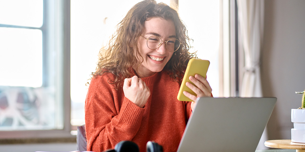 Woman holding a phone, smiling and pumping her fist after getting the job she wanted by using a talent-matching platform