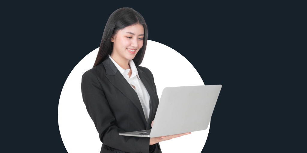A woman standing, looking down a laptop in her hands as she works