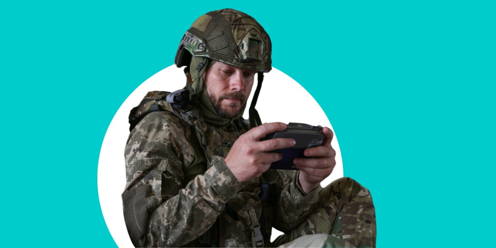 A soldier in military gear using a tablet or computer