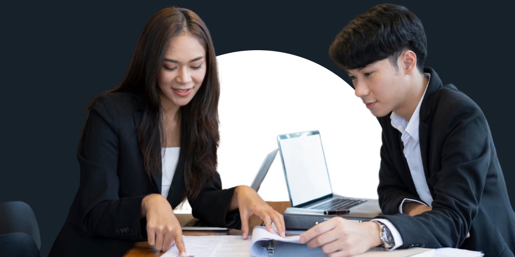 Two young working professionals working on laptops and collaborating