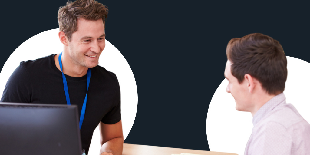 A young teacher working with a student or young professional in front of a computer