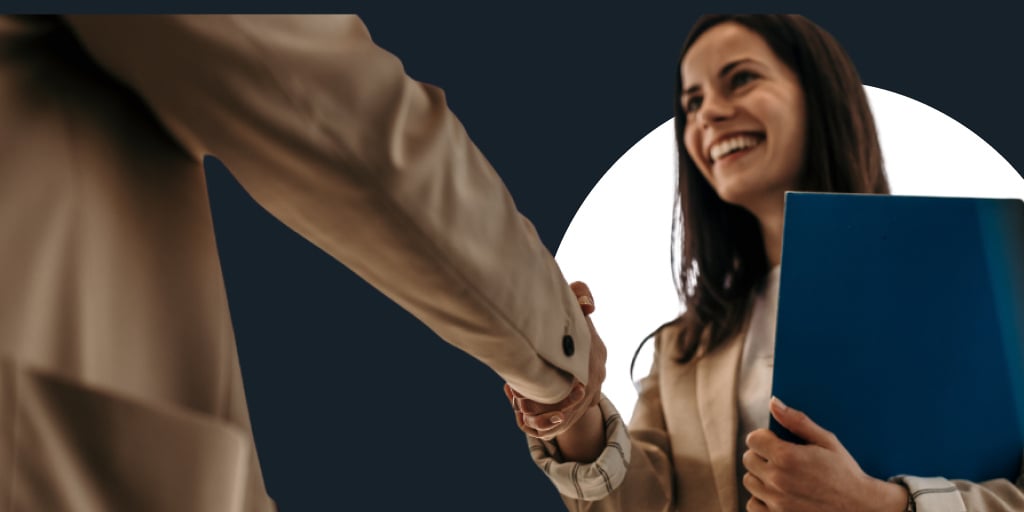 A young woman with work in hand shaking someone else's hand