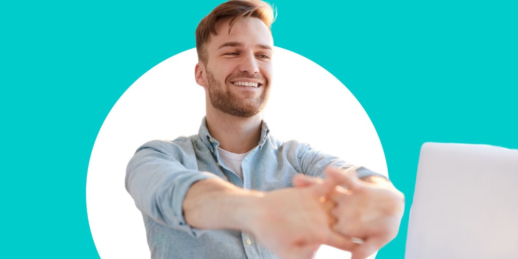 Young male worker stretching and smiling in front of his work station