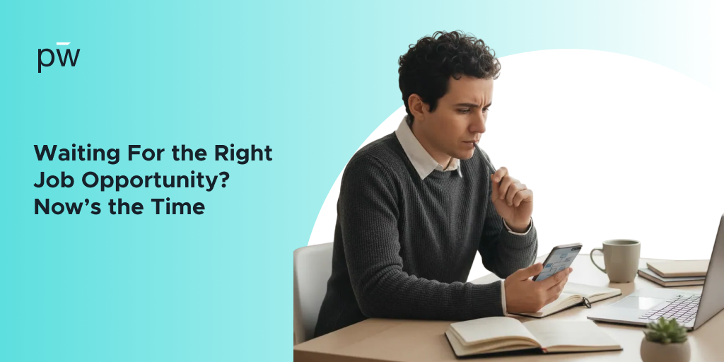 A man sitting and working on a laptop, while also looking at his phone