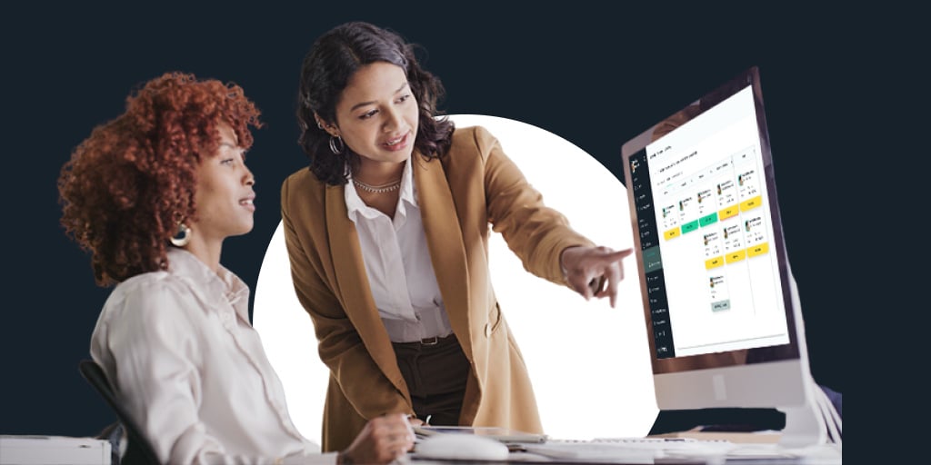 A woman who looks like a teacher helping another young woman in front of a computer