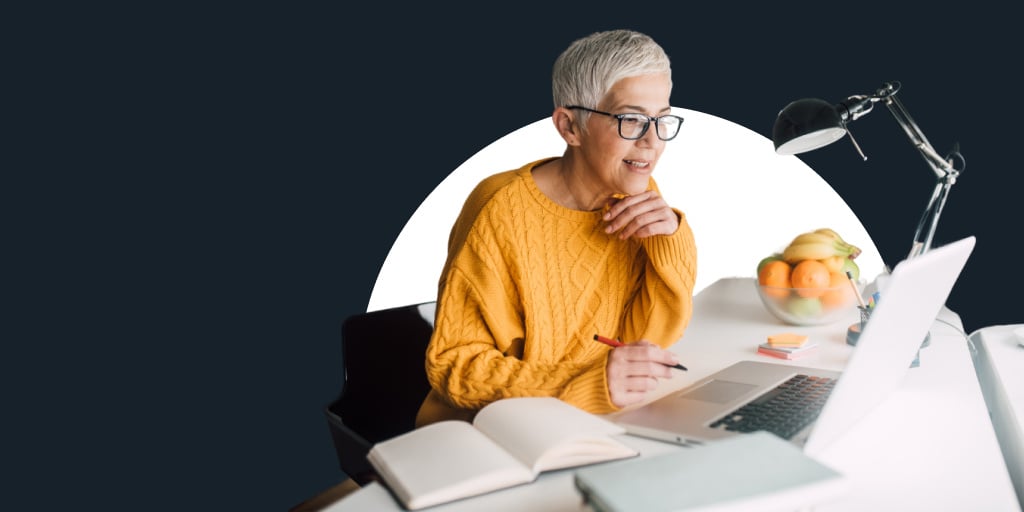 An older individual sitting at a desk writing