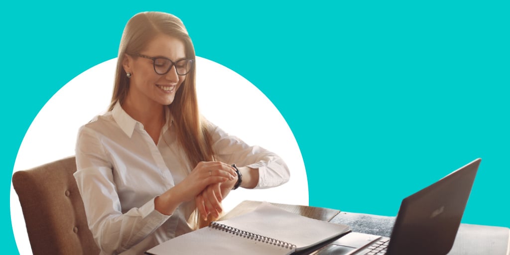 A woman reading and checking her watch sitting at a desk