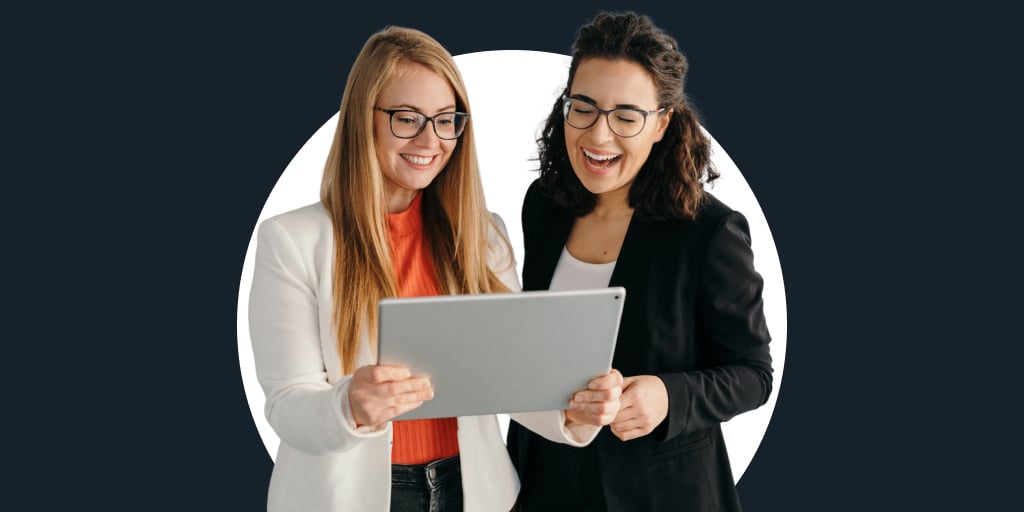 Two women looking at a tablet collaborating during work