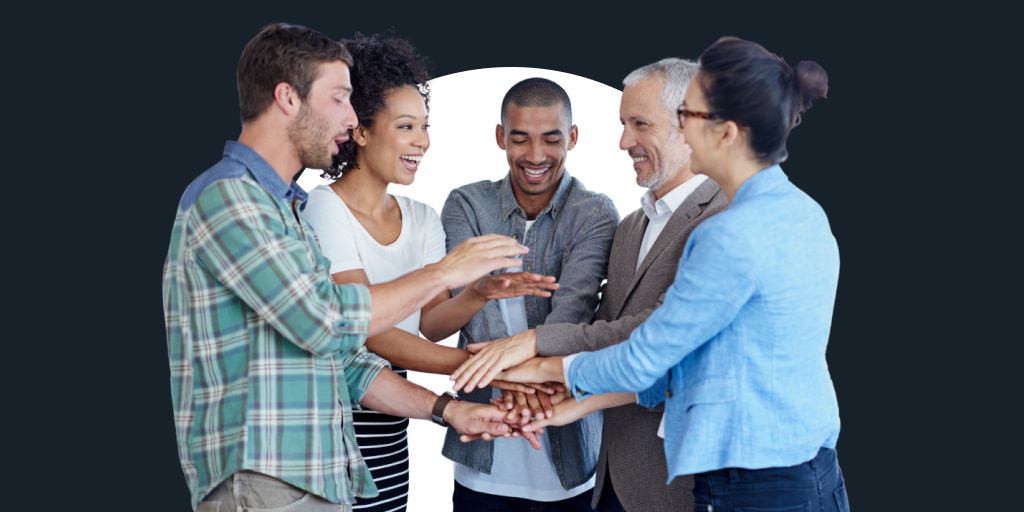 Multiple people in a group putting their hands in the center in solidarity