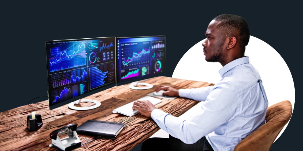 A man sitting in front of multiple monitors working on his computer