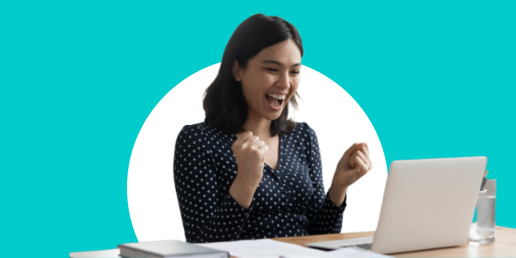 An excited woman cheering as she sits in front of a computer