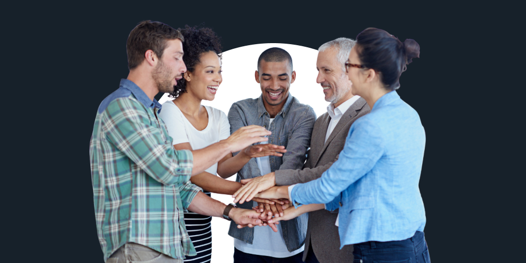A group of workers all smiling, as they put their hands in the middle of a circle as display of working as a team
