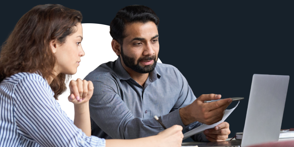 A group of people listening as someone instructs them as they work on a computer