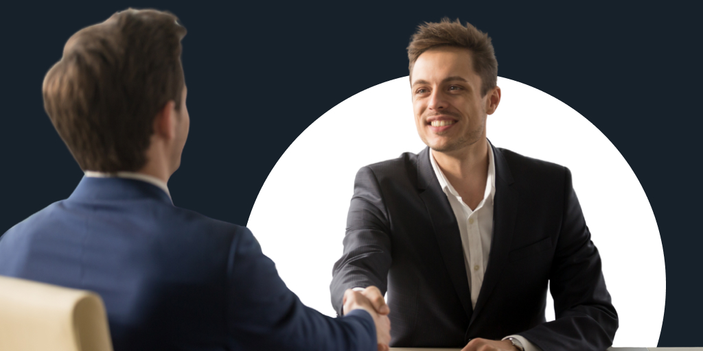 Well-dressed professionals, as one reaches across the table and shakes the other's hand