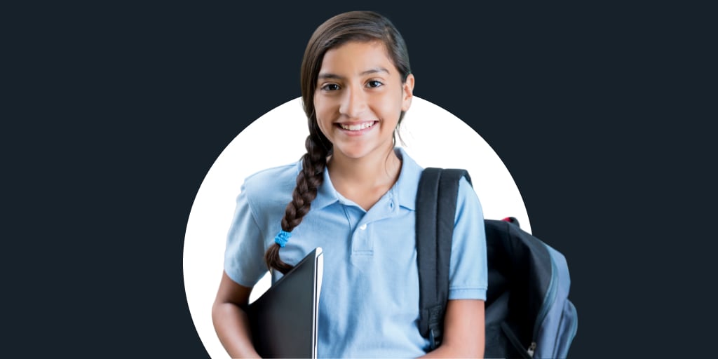 A young student carrying a laptop under her arm and backpack over her shoulder