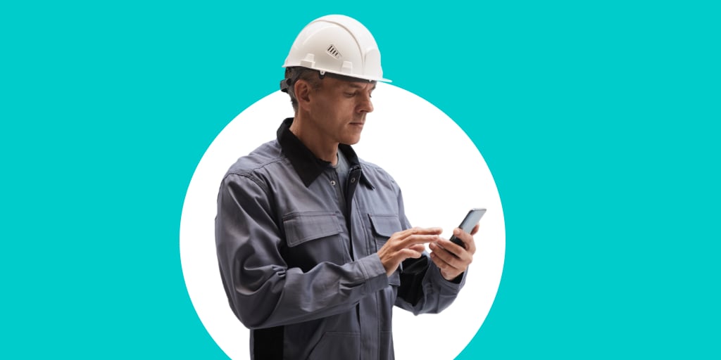 A worker wearing a construction hat while working on a phone device