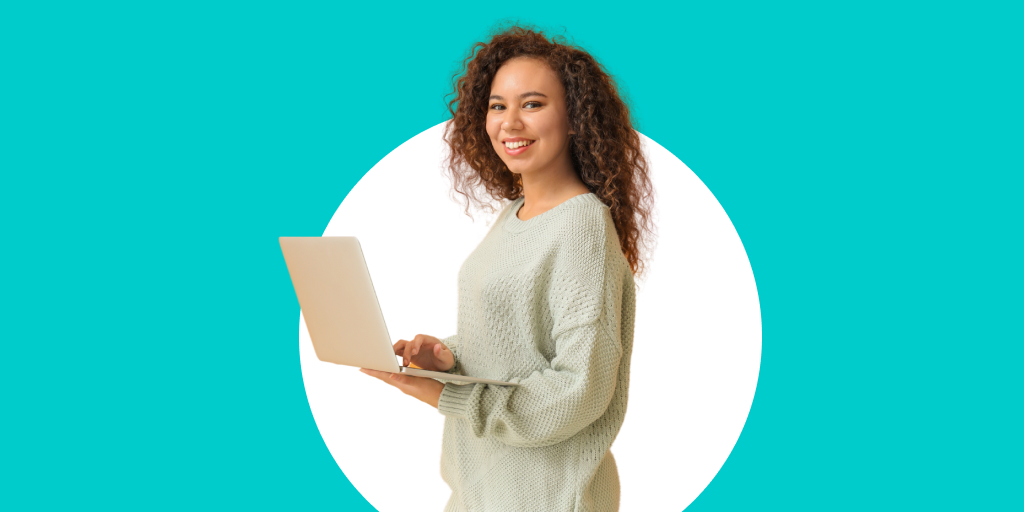 A woman standing, smiling, while working on a laptop in her hands