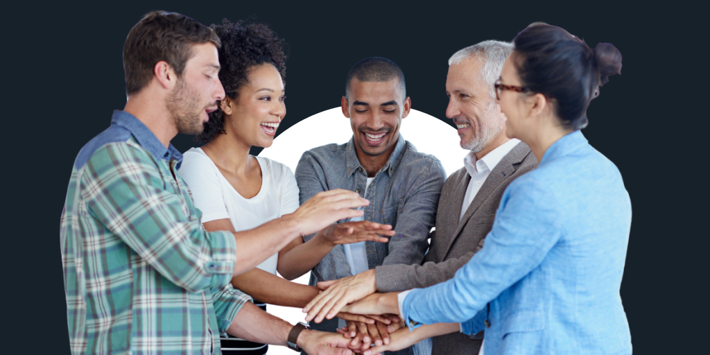 A group of well-dressed workers all putting their hands in the middle of a circle in a teambuilding ritual