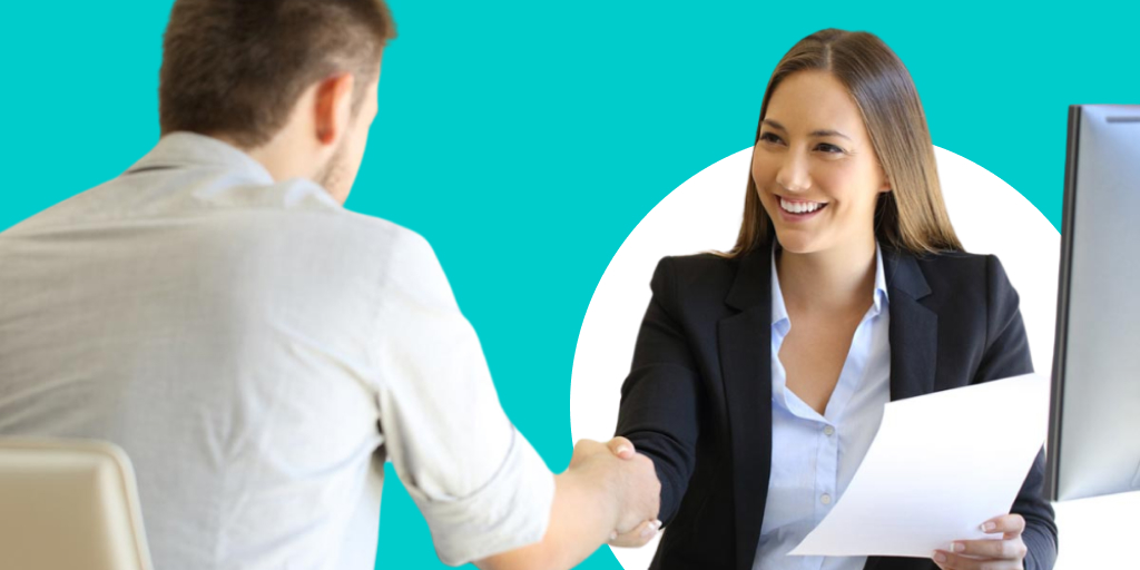A professional sitting down while shaking someone's hand sitting across from them at a desk
