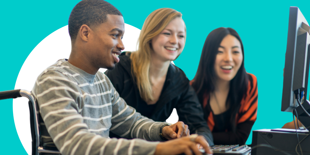 Three people standing and working at a laptop, while one types and the others look on smiling