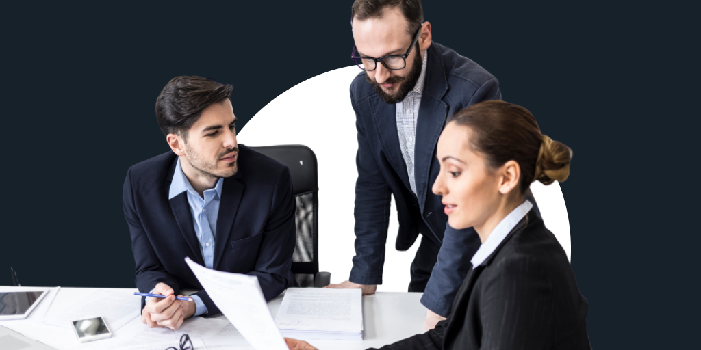 A group of workers sitting down, working together as they look at papers and reports