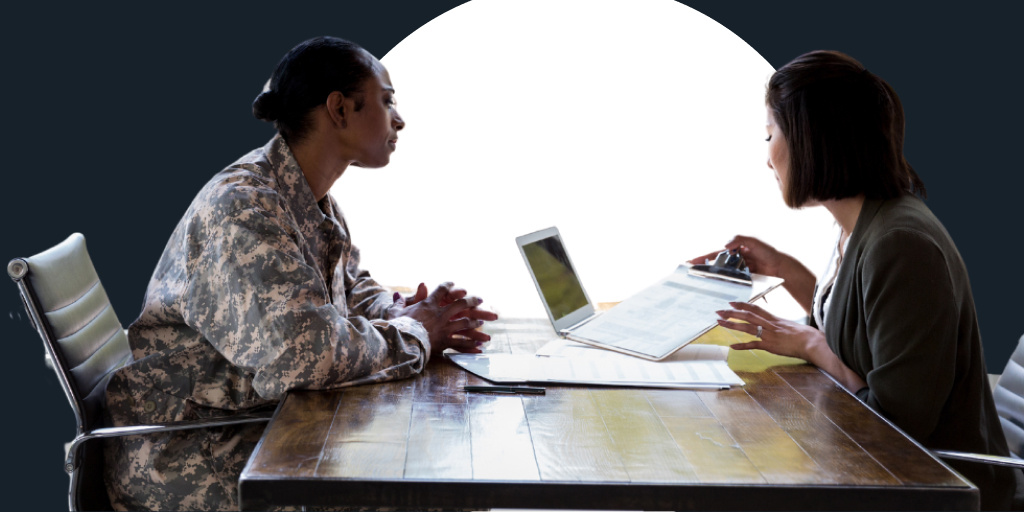 A female soldier sits down with a female officer worker while having a conversation