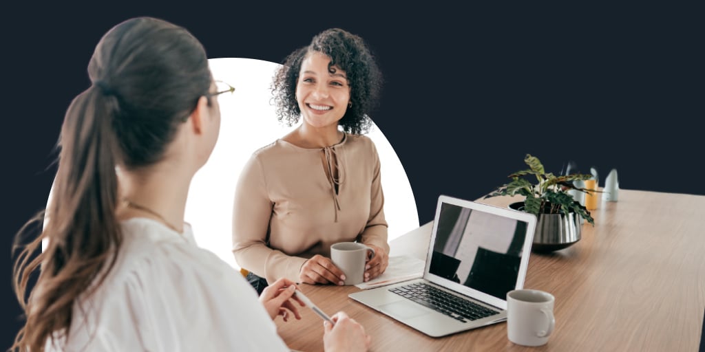 Two women working and sitting together as the collaborate on a laptop