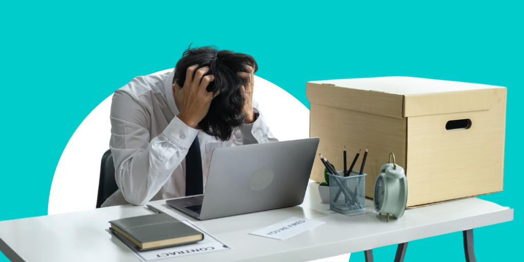 Man in office attire in front of a computer clearly upset with his head down