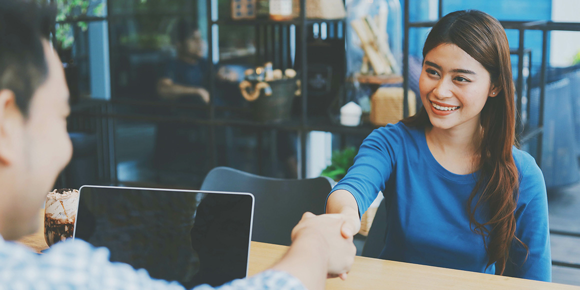 Student transitioning from college to a career shakes the hand of a new colleague